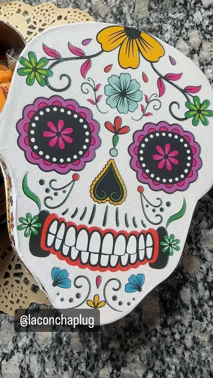 A hand-decorated sugar skull concha with marigolds, hearts and swirls
