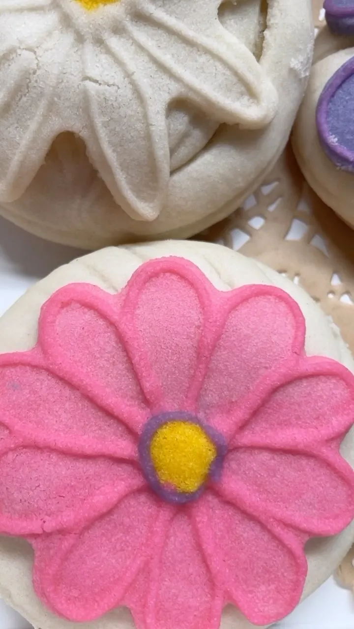 Close-up of a concha topped with a pink daisy design