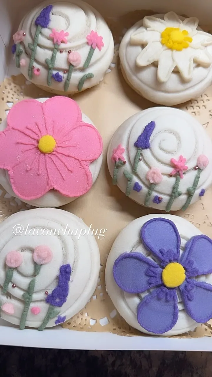 A box of conchas decorated with pink, purple and white flowers